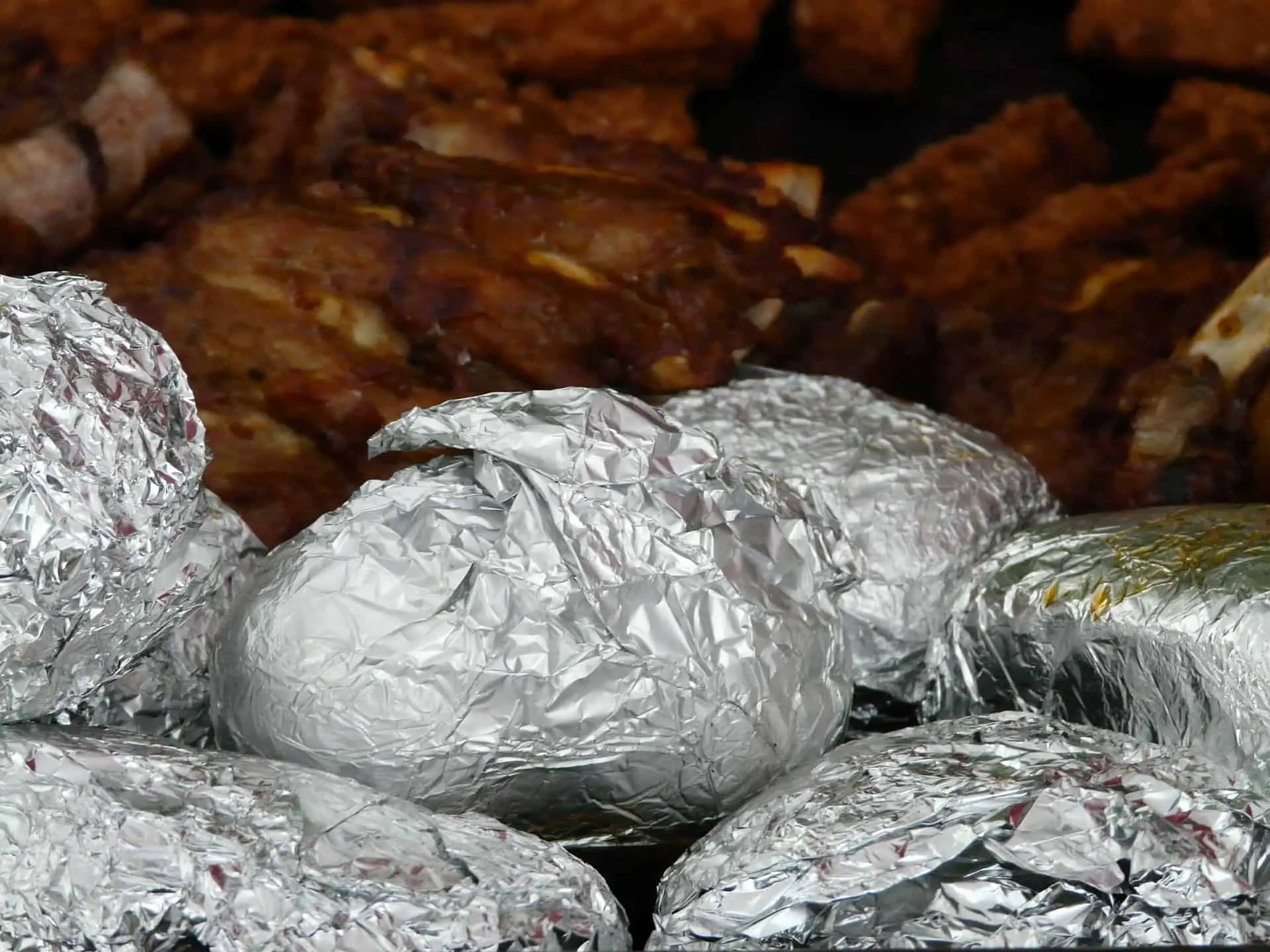 Baked Potatoes inside the oven and some are wrap with aluminum foil